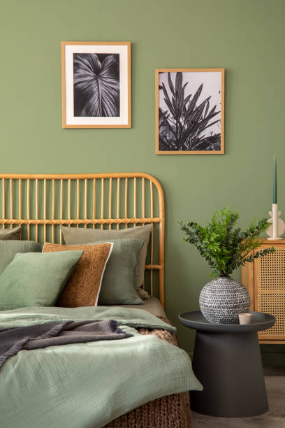 istock Stylish bedroom interior design with mock up poster frames, bed, side table, rattan commode, vanity table and creative home accessories. Sage green wall. Template. Copy space. 1404851759