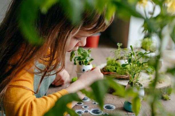 istock Little girl decorating eggshell with toy eyes on the table 1404852079