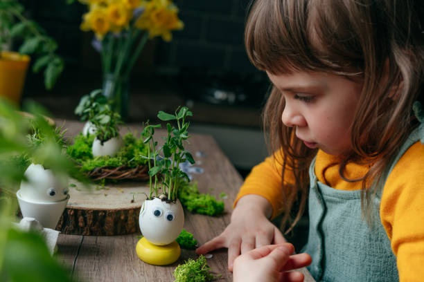 istock Little girl decorating eggshell with toy eyes on the table 1404852676