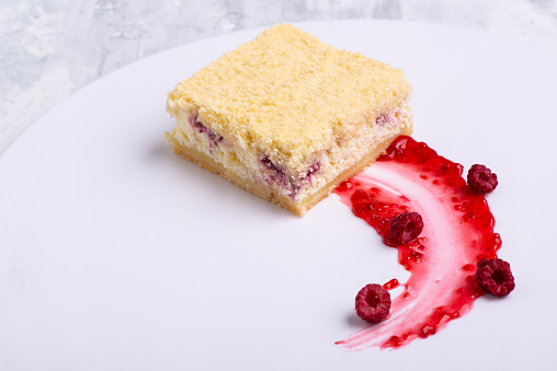 A serving of delicious vanilla rapsberry cake on a white plate