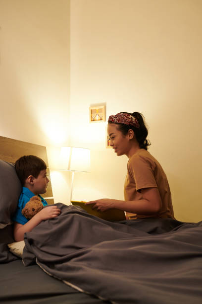 istock Smiling Mother Reading for Preteen Son 1404860198