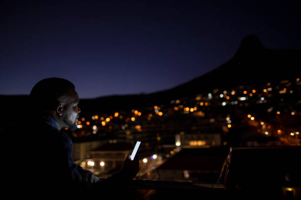 istock Businessman holding illuminated phone looking over cityscape at night 1404860698