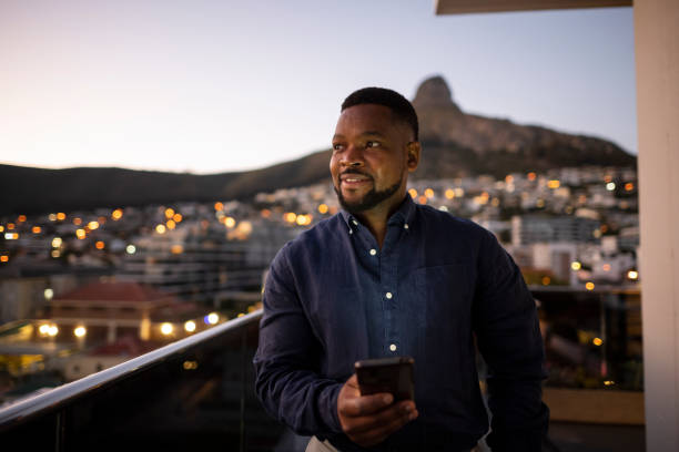 cándido hombre de negocios de retratos sosteniendo el teléfono mirando hacia la ciudad - montaña de lions head fotografías e imágenes de stock