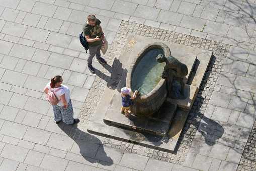 Magdeburg, Germany – April 29, 2022: Family with child seeks cooling at a fountain in the summer in the city center of Magdeburg in Germany