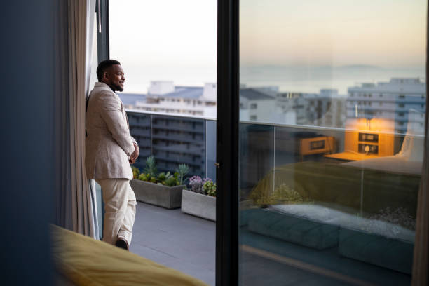 Businessman looks out from penthouse at dawn
