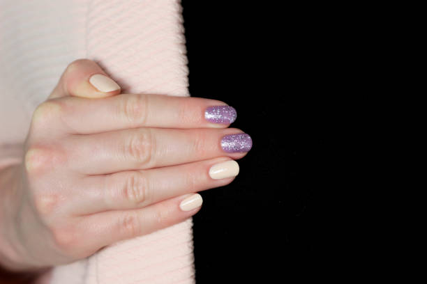 istock one hand with nude manicure and purple glitter design on black background 1404862279