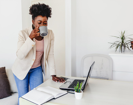 Portrait of a young businesswoman enjoying a beverage at work. Shot of a young businesswoman enjoying a cup of coffee while working at her desk in the office. Young female professional is working from home.