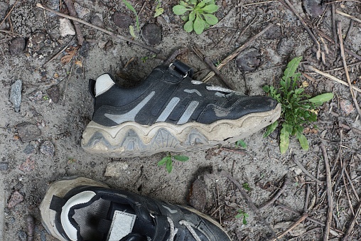 two old black sneakers lie on the gray ground on the street