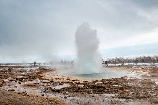 Geysir (named Stokkur) in Iceland, half-way the explosion. People are watching