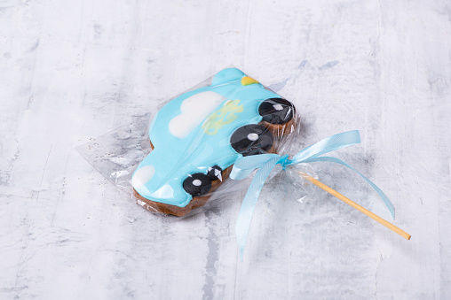 A closeup shot of a blue car-shaped cookie on a stick