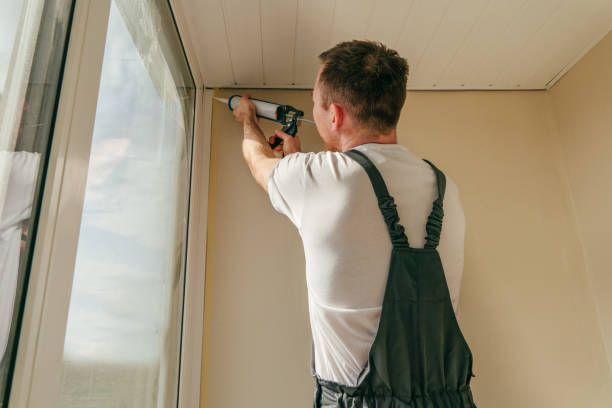 istock Young man wearing overalls sealing cracks between window and trim 1404866710