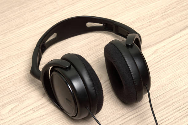 istock Black headphones with cable are on the wooden table 1404867501