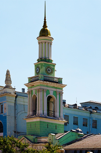 Ancient bell tower with clock at the blue sky background. The former Greek monastery in the Kontraktova Square. Kyiv, Ukraine.
