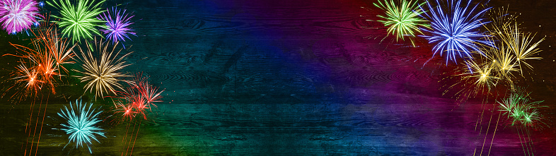 Happy new Year Silvester background banner panorama long- Colorful firework on rustic wooden texture in rainbow colors