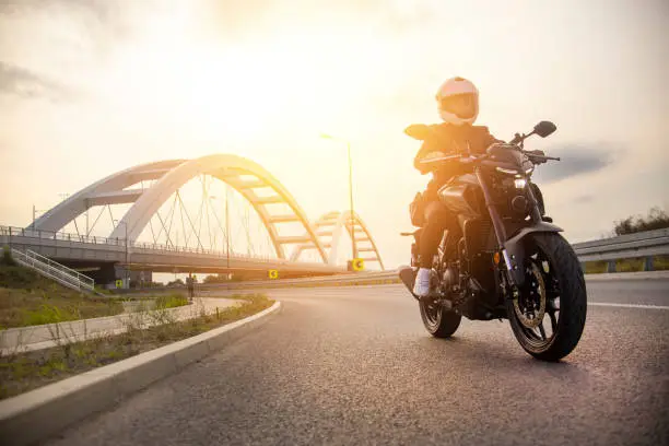 Young woman riding a motorcycle on a road. About 25 years old, Caucasian female.