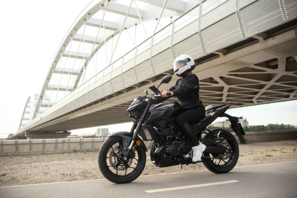 a person riding a black motorbike on a bridge