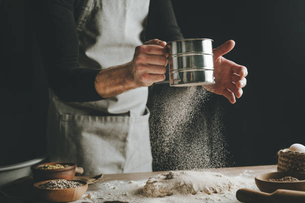 istock Young man kneading dough on dark background. 1404874861