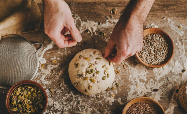 istock Young man kneading dough on dark background. 1404875108