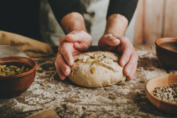istock Young man making whole wheat bread with sunflower and pumpkin seeds 1404875120