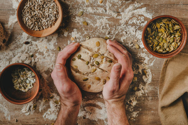 giovane che fa il pane integrale con semi di girasole e zucca - bread making foto e immagini stock