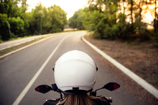 Young woman riding a motorcycle on a road. About 25 years old, Caucasian female.