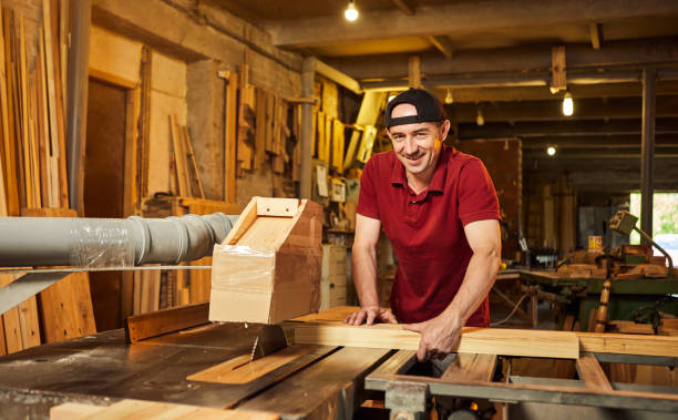 istock Professional carpenter in uniform works on a woodworking machine at the carpentry manufacturing 1404876553