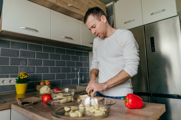 istock Young man cooking vegetables in the kitchen 1404877490