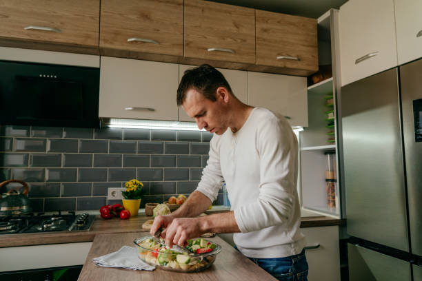 istock Youth man cooking fish and vegetables in the kitchen 1404878050