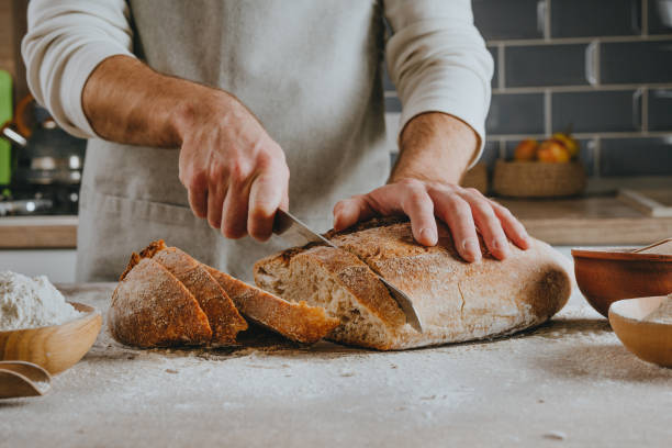 istock Young man in apron cutting homemade bread 1404878262