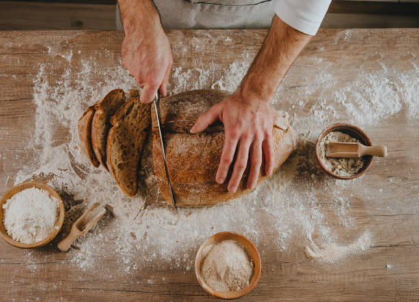 istock Young man in apron cutting homemade bread 1404878341