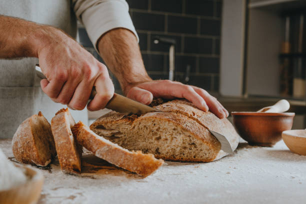 istock Young man in apron cutting homemade bread 1404878519