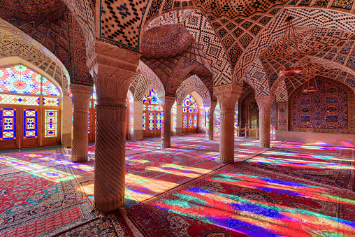Shiraz, Iran - 31 October, 2018: Awesome empty prayer hall at the Nasir al-Mulk Mosque (Pink Mosque). Amazing morning view of sunlight reflected through colorful stained glass windows on the floor.