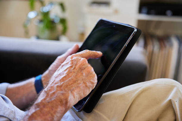 istock Senior man sitting on a sofa at home and using a tablet 1404883847
