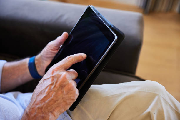istock Senior man working on a tablet on his living room sofa at home 1404883880