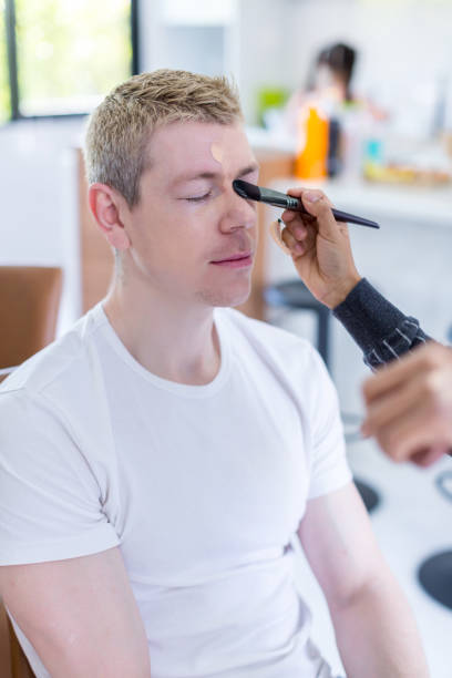 istock Stylist is putting make up on man. 1404884060
