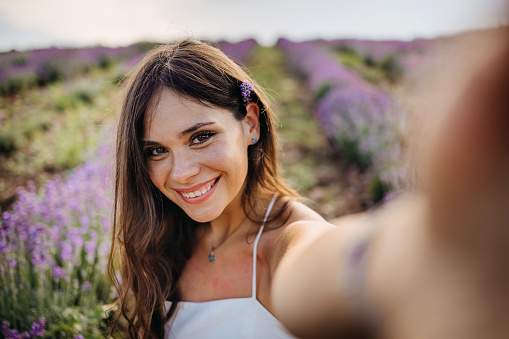 Happy woman taking selfie with phone in lavender field