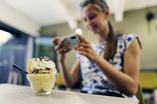 Teenage girl taking photos of her ice cream dessert and posting it on social media\nCanon R5