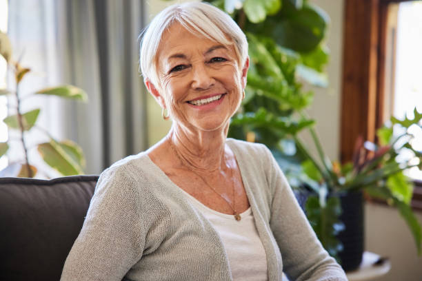 istock Senior woman smiling while sitting on her living room sofa 1404884940