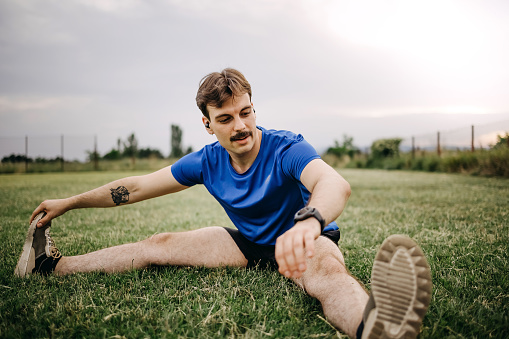 Young male sportsman in headphones doing sports exercises  outdoors