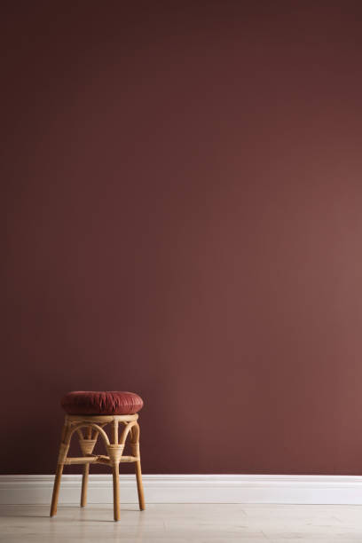 istock Stylish wooden stool with cushion near color wall, space for text. Interior element 1404888438