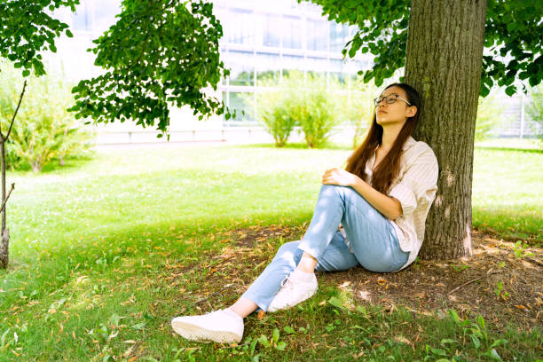 istock Young Chinese woman sitting sleeping in shadow under green tree on sunny day 1404888496