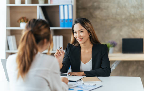 istock Young Happy Businesswoman Using Computer in Modern Office with Colleagues. Two female colleagues in office working together. 1404891103