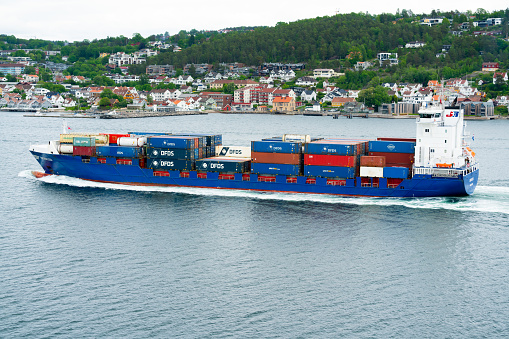 Oslo, Norway - June 22nd 2022: Container Feeder Ship sailing out through a fjord in Norway, fully loaded with goods and cargo for the Baltic region.