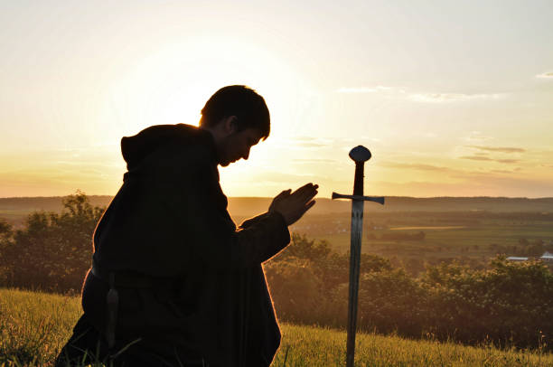 Praying knight in the sunset Medieval young male kneeing and praying Our father in the evening with a sunset. excalibur stock pictures, royalty-free photos & images