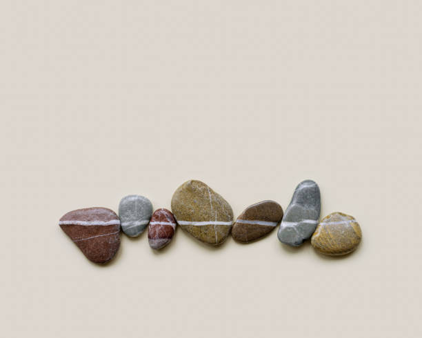 istock Aesthetic minimal flat lay sea pebble stones with white line, beige background. Composition from natural colored stone on the same level. Balance or harmony concept, horizontal row rocks. 1404900272