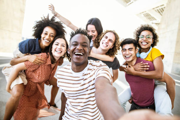 도시 거리에서 스마트 휴대 전화로 셀카 그룹 사진을 찍는 다인종 친구 - 카메라를보고 함께 웃고있는 행복한 젊은이들 - 십대들이 놀고있는 청소년 라이프 스타일 개념 - 18 19세 뉴스 사진 이미지