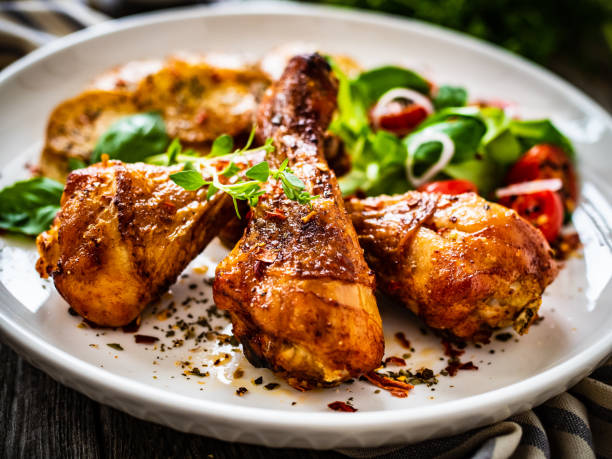 istock Barbecue chicken drumsticks with chips and greens on wooden table 1404901333