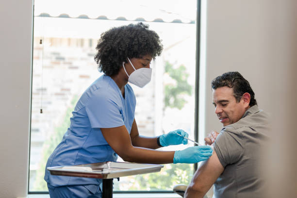 istock Nurse in protective mask and gloves gives man vaccination 1404901833