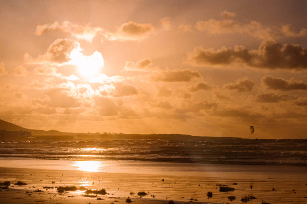 wunderschöner orangefarbener sonnenuntergang mit einer person, die sky surf in famara, lanzarote macht - famara stock-fotos und bilder