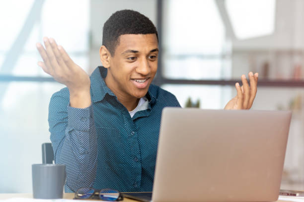 istock Man working using laptop. Young Afro American businessman, talking with colleagues or partners on video call sitting in a modern office, discussing something 1404905003